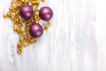 Gold beads and purple toys on white wood, horizontally with copy space