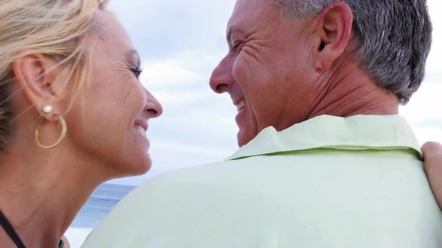Close up of an older couple at the beach with their arms around each other and being affectionate