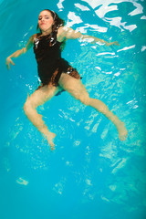 Woman floating relaxing in swimming pool water.