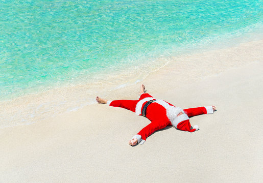 Santa Claus sunbathe on sand at beach, Christmas greeting card