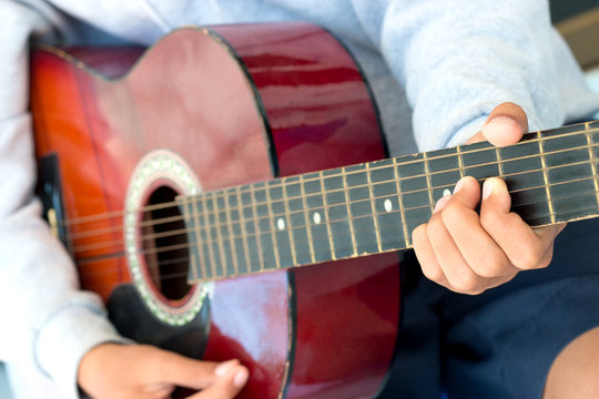 blurred boy's hands playing old acoustic guitar, and teaching