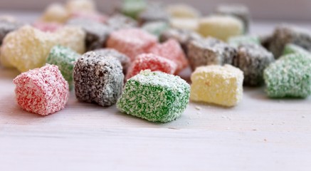 Turkish delight sweetness colorful in coconut flakes on a light wooden table