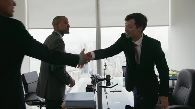 Clients meeting with consultant in corporate office. The team of business people shakes their hands and sit down talking. Medium shot, Steadicam