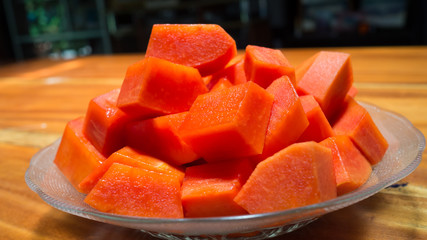 Sliced of freshly yellow orange papaya in glass plate on wood table