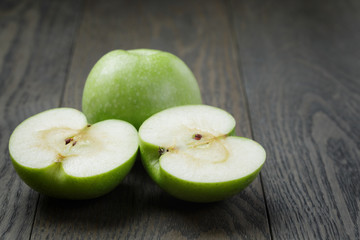 ripe green apples sliced on wood table