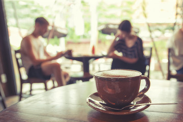 Cup of coffee on table in cafe with people retro instagram effect - shallow depth of field