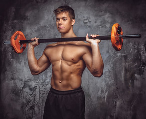 Shirtles muscular young guy holds barbell.