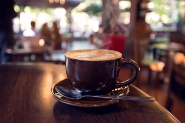 Cup of coffee on table in coffee shop with people; - shallow depth of field