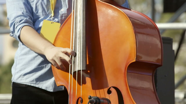 Classical double acoustic bass musician practing outside in daylight