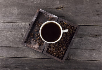 Cup of coffee and coffee grains in box on a wooden background