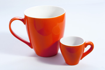 Two orange cups on briht surface, one small for coffee, one large for tea