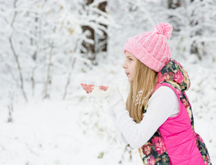 Young girl blows off snowflakes from palm
