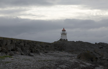 A light house on a beach and a constrasty sky