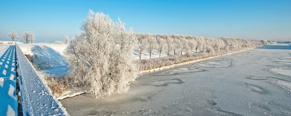 Frozen canal in winter under a blue sky 