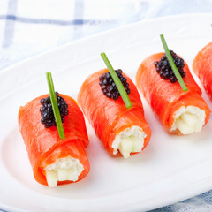 Smoked salmon rolls with cream cheese, black caviar