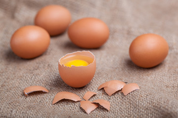 Fresh eggs on sacking, broken eggshell, yolk