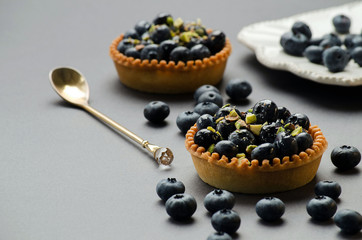 tarts with blueberries, a spoon and a saucer of berries