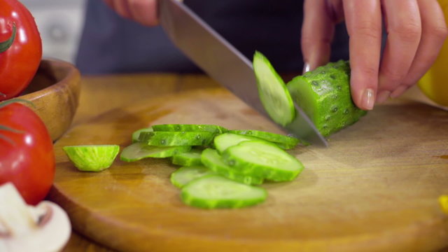 chef chopping a cucumber for a salad closeup slow motion