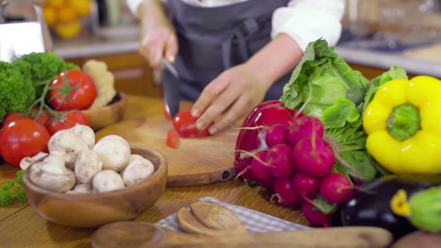 chef cutting slices of tomato for salad slow motion