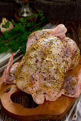Raw chicken with spice, prepared for roasting on a wooden table