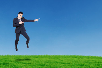 Happy businessman jumping and pointing something