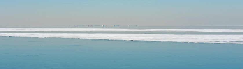 Fototapeta na wymiar Boats sailing along an ice sheet in winter