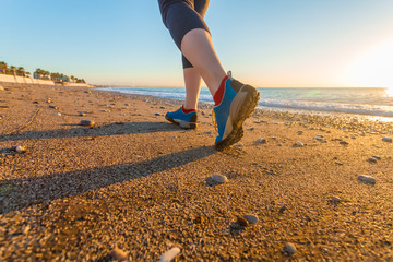 Young Woman jogging on Sand Beach along Sea Surf at Sunrise Shoes Close Up