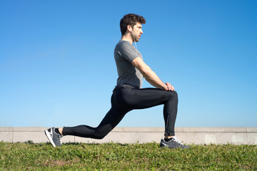 Man makes strechings before running in the grass