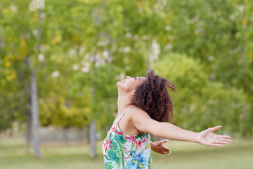 Obraz premium Woman stretching her arms out behind her in a green park