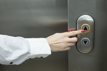 Female hand pressing elevator up button
