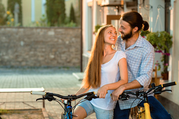 happy young couple of bicyclists talking in the street