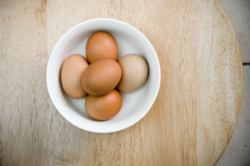 the five eggs in white ceramic bowl on wood table