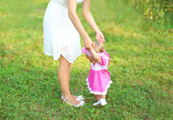 Beautiful mother and baby walking together on grass in summer da