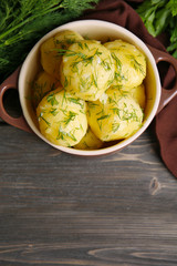 Boiled potatoes with greens in bowl on table close up