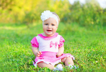 Happy cute smiling little girl child sitting on grass in summer