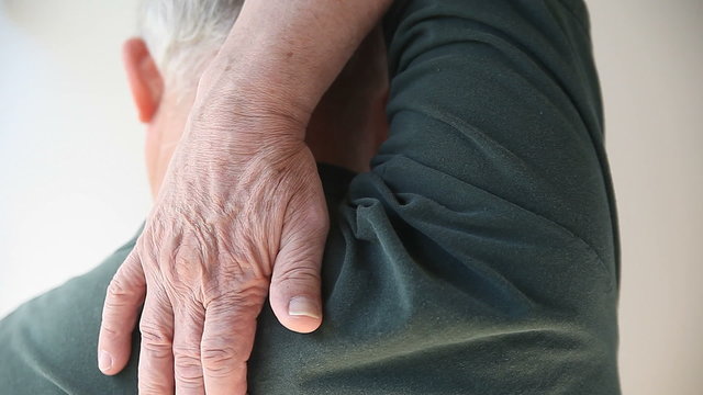 A senior man tries to reach an itchy spot on his back.
