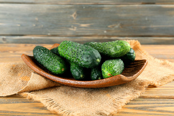 Fresh cucumbers in rustic bowl on  wooden background