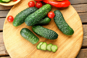 Composition of cucumbers, tomatoes and sweet peppers circles on wooden background, close up