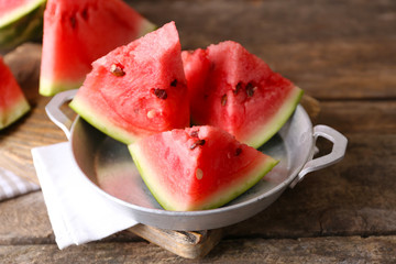 Sliced watermelon in metal bowl on wooden background