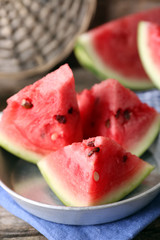 Sliced watermelon in metal bowl on decorated wooden background