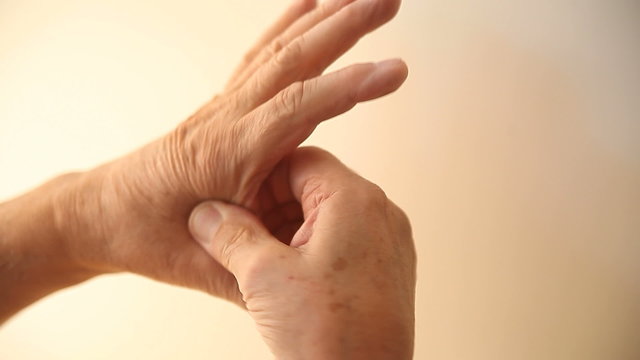 A man rubs the painful area between his index finger and thumb.
