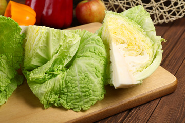 Cut savoy cabbage and pepper on wooden cutting board closeup