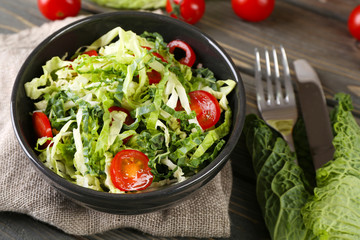 Savoy cabbage and tomato salad served in bowl on wooden table