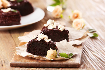 Piece of chocolate cake decorated with flowers on brown wooden table