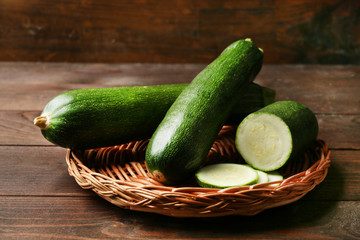 Fresh zucchini on wicker mat on wooden background
