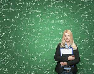 young girl holding note books, green blackboard with signs at th