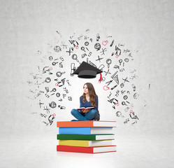 woman on pile of books a book on her knees thinking about educat