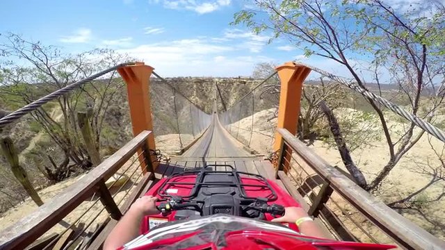 First person POV of a four wheeler about to drive across a hanging bridge