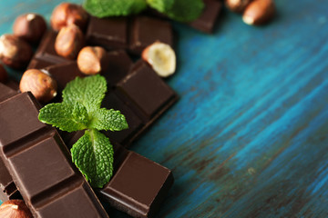 Chocolate pieces with nuts on color wooden background