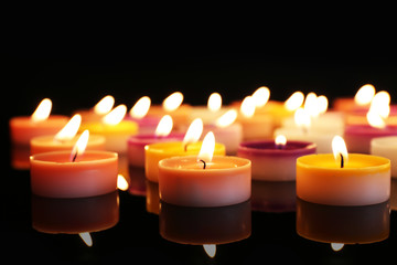 Many burning small candles on dark background